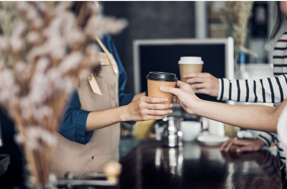 Image of people exchanging coffee cups to show how coffee shops are redefining Bulacan’s local culture