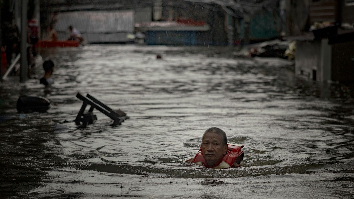 A man survives on a floater while walking thru flooded waters as Greenpeace issues urgent call from PH government to protect climate funds